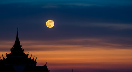 Stunning full moon rising over temple silhouette during vibrant sunset, peaceful evening