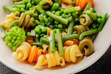 Trottole pasta vegetables green peas, green beans, kohlrabi cabbage, broccoli second course tasty snack fresh delicious gourmet food background on the table rustic food top view copy space