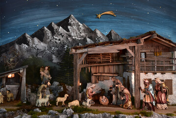 Weihnachtskrippe im alpenländischen, ländlichen Stil, mit Bergen und Nachthimmel als Hintergrund, in gemütlichem Stall aus alten Holzbalken und stimmungsvoller Beleuchtung