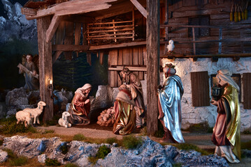 Weihnachtskrippe im alpenl&auml;ndischen, l&auml;ndlichen Stil, mit Bergen und Nachthimmel als Hintergrund, in gem&uuml;tlichem Stall aus alten Holzbalken und stimmungsvoller Beleuchtung