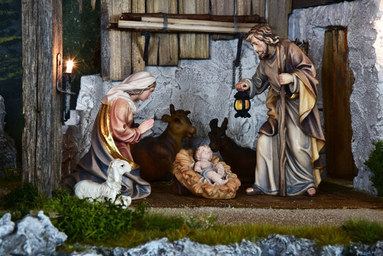 Weihnachtskrippe im alpenl&auml;ndischen, l&auml;ndlichen Stil, mit Bergen und Nachthimmel als Hintergrund, in gem&uuml;tlichem Stall aus alten Holzbalken und stimmungsvoller Beleuchtung