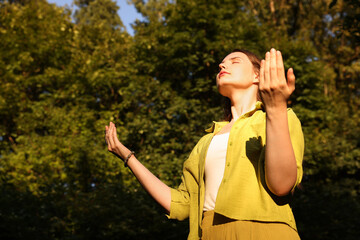 Woman meditating to heal or restore her aura in nature, space for text