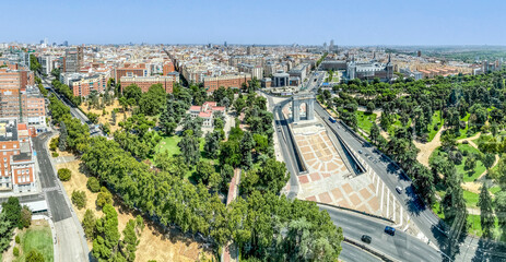 Parque del Oeste and the Arco de la Victoria stand majestically in this panoramic view of Madrid. The scene captures the vibrant mix of urban nature, monumental architecture, and everyday city life