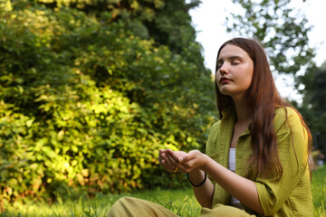 Woman meditating to heal or restore her aura in nature, space for text