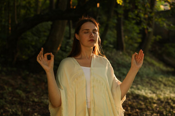 Woman meditating to heal or restore her aura in nature