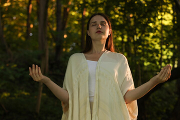 Woman meditating to heal or restore her aura in nature