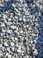 Background of smooth white stones and pebbles outdoors in sunlight