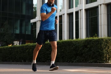 Fototapeta premium Man in sportswear running on city street, closeup. Space for text