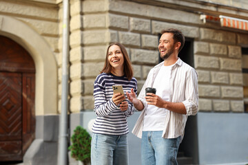 Coffee to go. Couple with paper cup of drink and smartphone outdoors, space for text