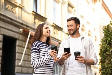 Coffee to go. Couple with paper cups of drinks and smartphone outdoors