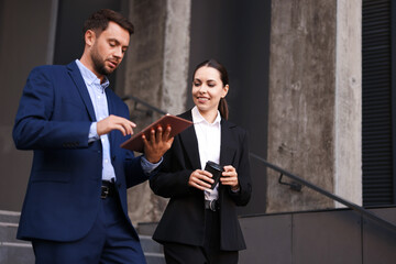 Coffee to go. Woman with paper cup of drink and her business partner during meeting outdoors, space for text