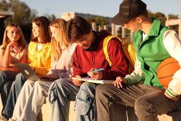 Group of teenagers doing homework together outdoors