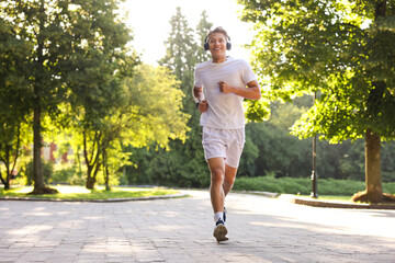 Fototapeta premium Happy man with headphones running in park