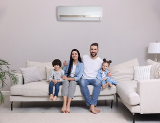 Happy family on sofa in living room. Air conditioner keeping comfortable temperature in room