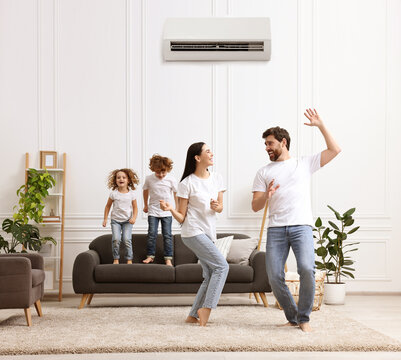 Happy family having fun in living room. Air conditioner keeping comfortable temperature in room