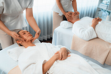 Fototapeta premium Caucasian couple enjoying relaxing anti-stress head massage and pampering facial beauty skin recreation leisure in dayspa modern light ambient at luxury resort or hotel spa salon. Quiescent