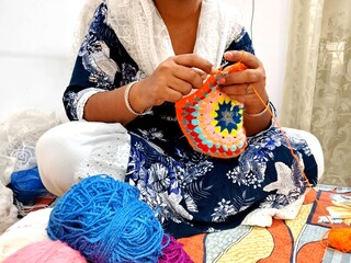 brown hands crocheting colorful yarn. multicolor yarn wool textured pattern for crochet. colorful...