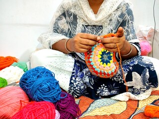brown hands crocheting colorful yarn. multicolor yarn wool textured pattern for crochet. colorful...