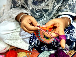 brown hands crocheting colorful yarn. multicolor yarn wool textured pattern for crochet. colorful...