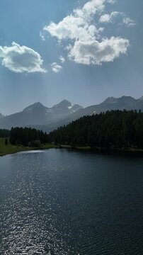 Aerial drone view of Lake Lej da Staz (Mej de Staz) surrounded by pine forest and mountains near St. Moritz in Engadin, Switzerland. Scenic alpine landscape with lakes, forests, and peaks. Perfect for