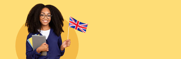 Happy young black student lady holding tablet and the UK flag, symbolizing international education,...