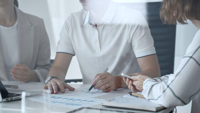 Professional team analyzing financial charts, working together in sleek workspace, strategizing company performance with collaborative energy and shared insights, close up