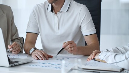 Professional team analyzing financial charts, working together in sleek workspace, strategizing company performance with collaborative energy and shared insights, close up