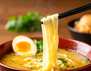 Steaming Ramen Noodles Held by Chopsticks over a Bowl with Egg and Broth