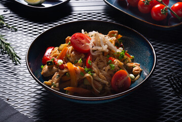 Noodles with Chicken and Vegetables on Dark Plate on Black Table, Top View