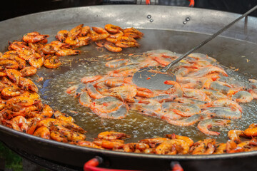 Large pan with shrimps frying in oil, half cooked and half raw, prepared for street food serving. Concept of fast food, street cooking, seafood delicacy, Mediterranean cuisine