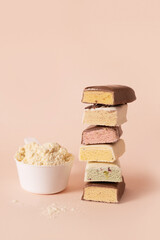 Different whey protein bars with various coatings and sprinkles scoop of protein powder on beige background. Fitness nutrition. Vertical format.