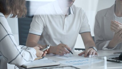 Professional team analyzing financial charts, working together in sleek workspace, strategizing company performance with collaborative energy and shared insights, close up