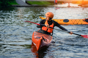 Participants paddle on a calm river at sunset, showcasing vibrant kayaks and a peaceful atmosphere. The water reflects the warm colors of dusk as outdoor enthusiasts engage in the sport