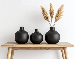 Three Black Vases with Pampas Grass on Wooden Table Against White Wall