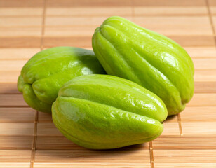 Three Fresh Green Chayotes on Bamboo Mat, Close-Up View