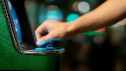 Close-up of hand starting to play green arcade machine dimly lit interior with blurred lights in background - Powered by Adobe