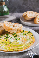 Fried eggs with zucchini noodles and ciabatta on a plate on the table vertical view