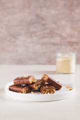 Protein bars with nuts on plate and protein powder in jar on table vertical view
