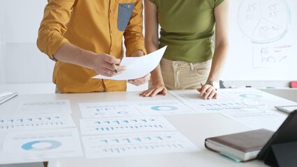 Professional team analyzing financial charts, collaborating intently around conference table in sleek, contemporary workspace. Business people concept