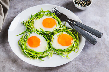 Fried eggs in zucchini noodle nests on a plate on the table