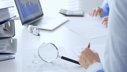 Business team working together, analyzing financial data on charts and documents, laptop and...