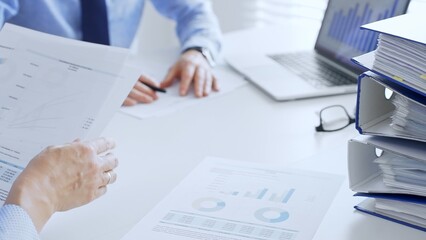 Business team working together, analyzing financial data on charts and documents, laptop and folders on white desk in office, close up of magnifying glass. Audit and taxes theme in business