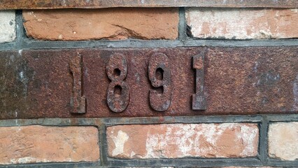 Rustic brick wall with vintage metal numbers "1891" embedded, perfect for historical or industrial-themed projects, interior design, or architectural photography