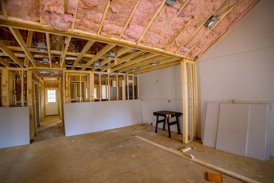 Construction team works on home interior renovation with exposed wood, insulation celling background.