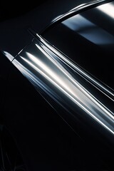 Close-up of a sleek, dark-colored car's rear quarter panel, showcasing its highly polished, reflective surface and smooth curves.  The dark background enhances the metallic sheen