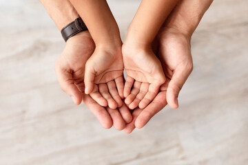 Care, Support And Growth. Cropped close up above top view of caring man holding girl's palms in hands, spending free time with daughter together at home. Children Custody Concept