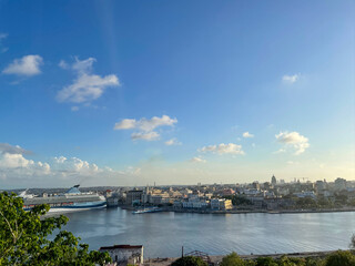 Large cruise ship docked in Havana Harbor, Cuba. City skyline and Capitol building in warm sunset light