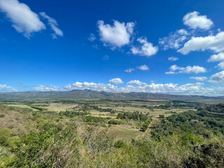 Wide valley view, distant mountains beneath the vivid blue sky and scattered clouds, in central Cuba, bright sunny day