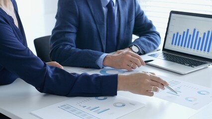 Business professionals reviewing financial data, pointing at laptop charts and shared documents during collaborative strategy session. Business people and finance concept