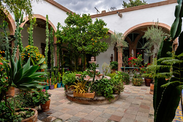Fototapeta premium Colonial courtyard garden with fountain and tropical plants in historic center of San Miguel de Allende, Mexico